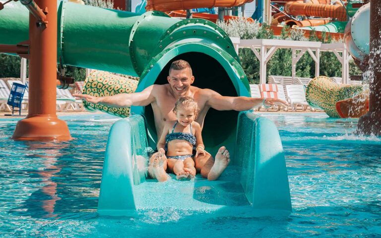 Father playing with his daughter in swimming pool. Funny family weekend. Father and daughter enjoy time together in water park.