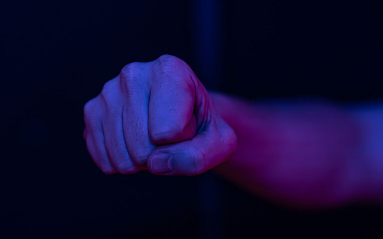 Close up of a male clenched fist in a dark room lighting.